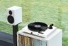 a record player on a white table with a speaker and vinyl records